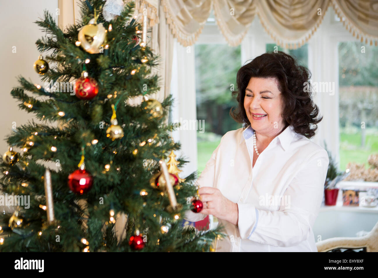 Senior woman decorating Christmas tree Stock Photo