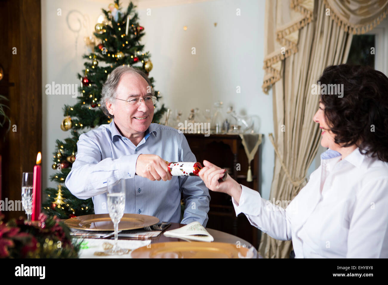 Senior couple opening Christmas cracker Stock Photo
