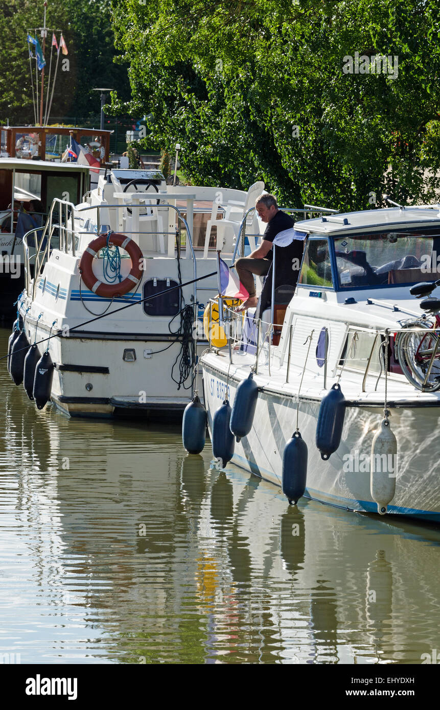 A man fishes from his live-aboard boat on the Canal du Centre, Fragnes, France. Stock Photo