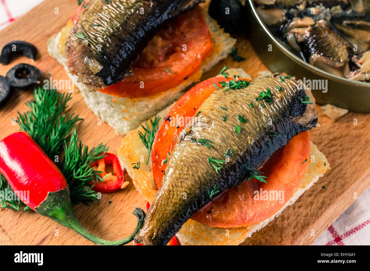 Toasts with a large smoked sardines. On the table hot peppers and