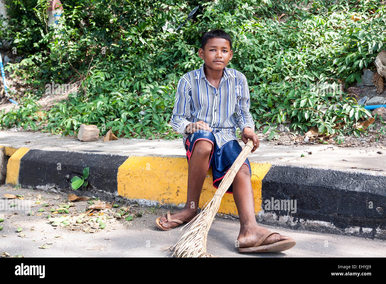 Cambodian boy pose for portrait after swept street with palm leaves broom in Kep, Cambodia. Stock Photo