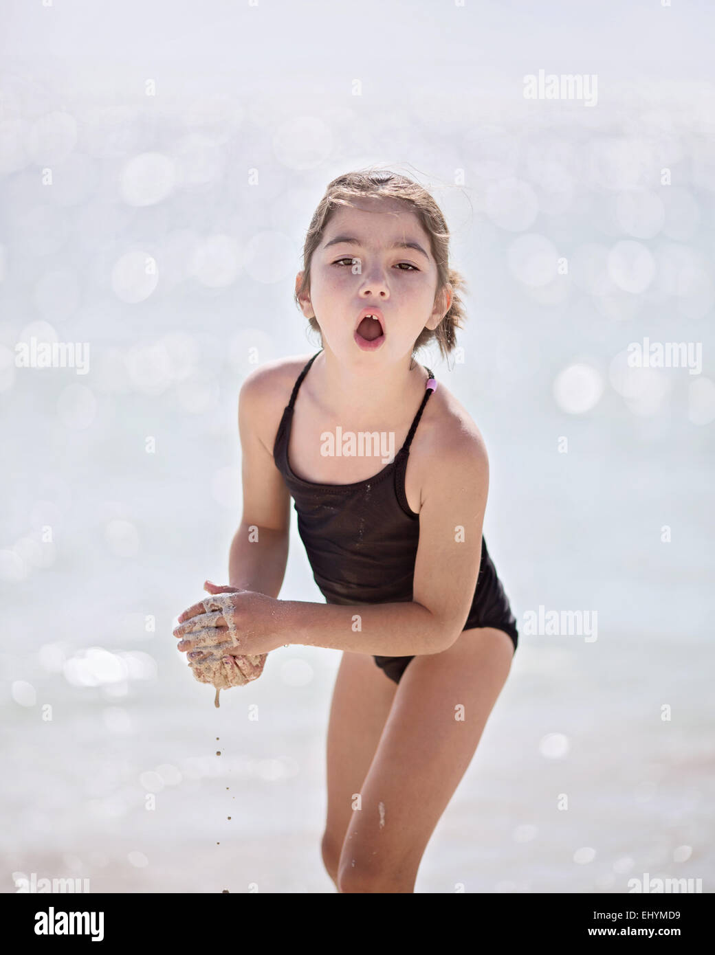 Girl standing on beach playing with wet sand, Mexico Stock Photo