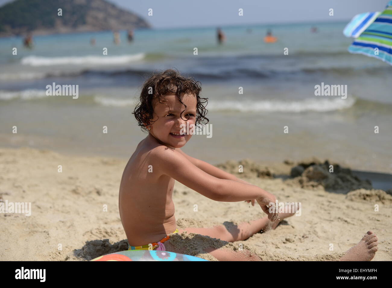Smiling girl playing in the sand on the beach, Thassos, Greece Stock Photo