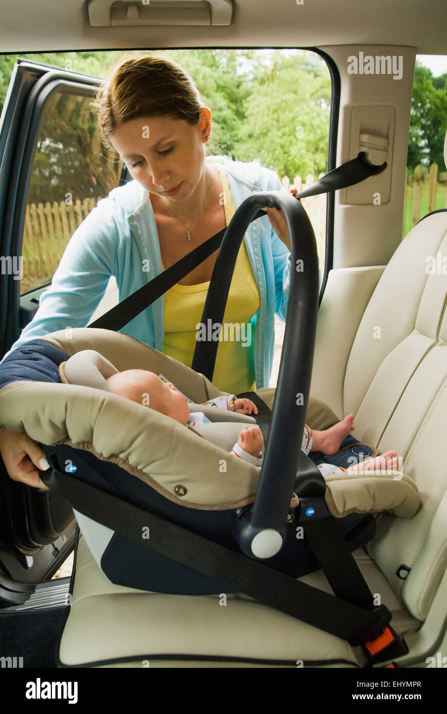 Mother strapping baby boy in car seat Stock Photo Alamy