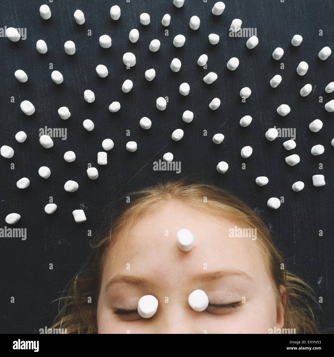 Girl with her eyes closed surrounded by marshmallows Stock Photo