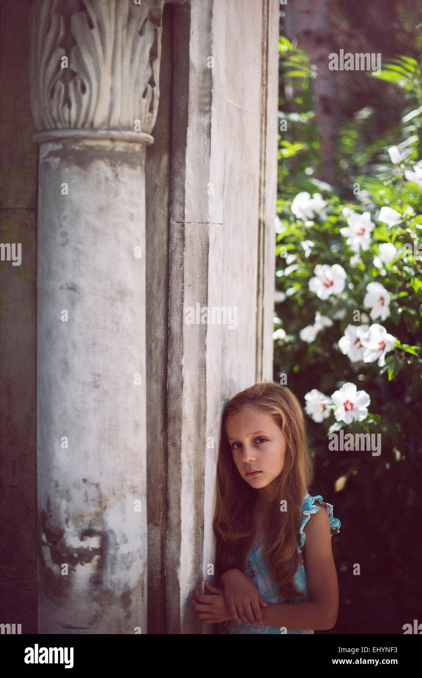 Sad girl standing by a column in the garden Stock Photo