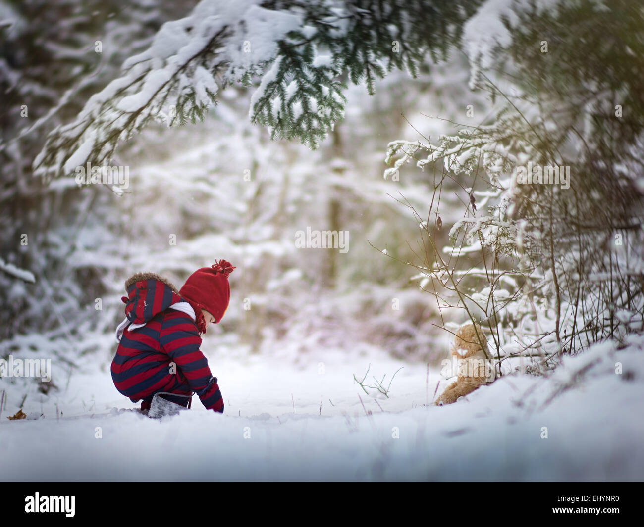 Baby boy playing in the snow with a teddy bear Stock Photo - Alamy