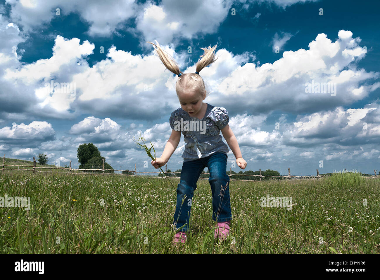 Girl jumping in the air in a summer meadow, Italy Stock Photo