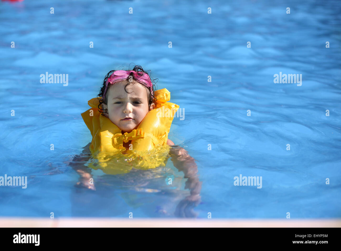 Girl in a swimming pool wearing a life jacket Stock Photo