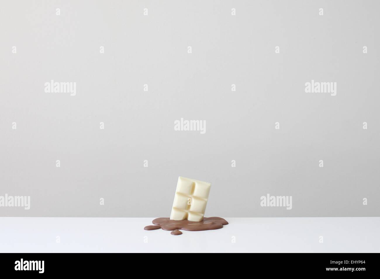 Conceptual bar of white chocolate in a pool of melted milk chocolate Stock Photo