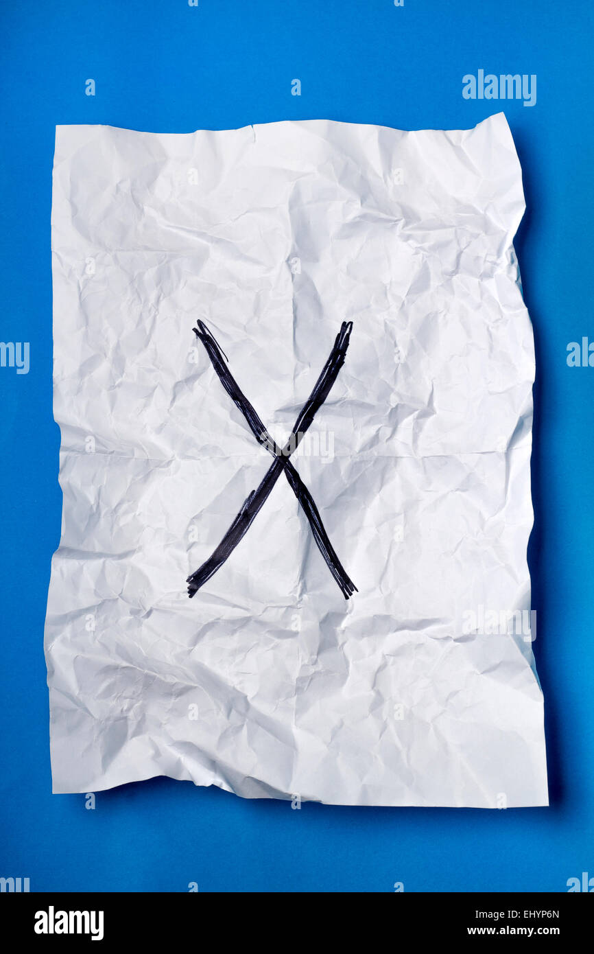Black cross on a wrinkled white piece of paper over a blue background ...