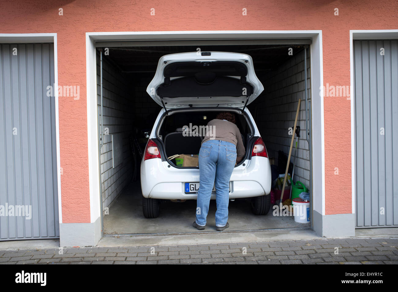 Woman getting shopping out of the boot of a small car Stock Photo