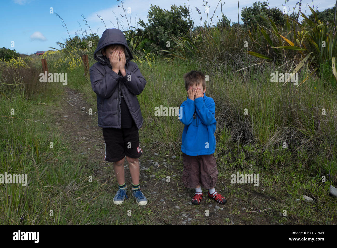 Children playing hide and seek in field Stock Photo