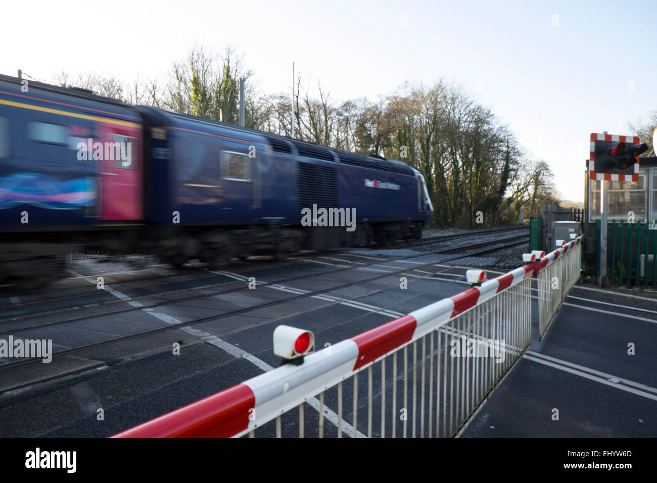 Train passes the closed gates of rail  level crossing, St Fagan's, Cardiff, Wales, UK Stock Photo