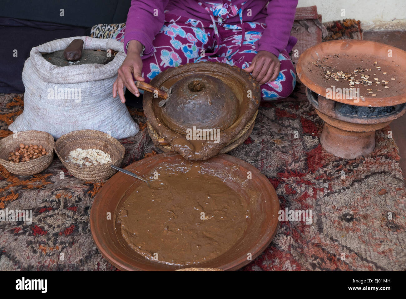 Woman grinding Argan (Argania spinosa) almonds  for the traditional manufacturing process of argan oil, Ourika Valley, Atlas Mou Stock Photo