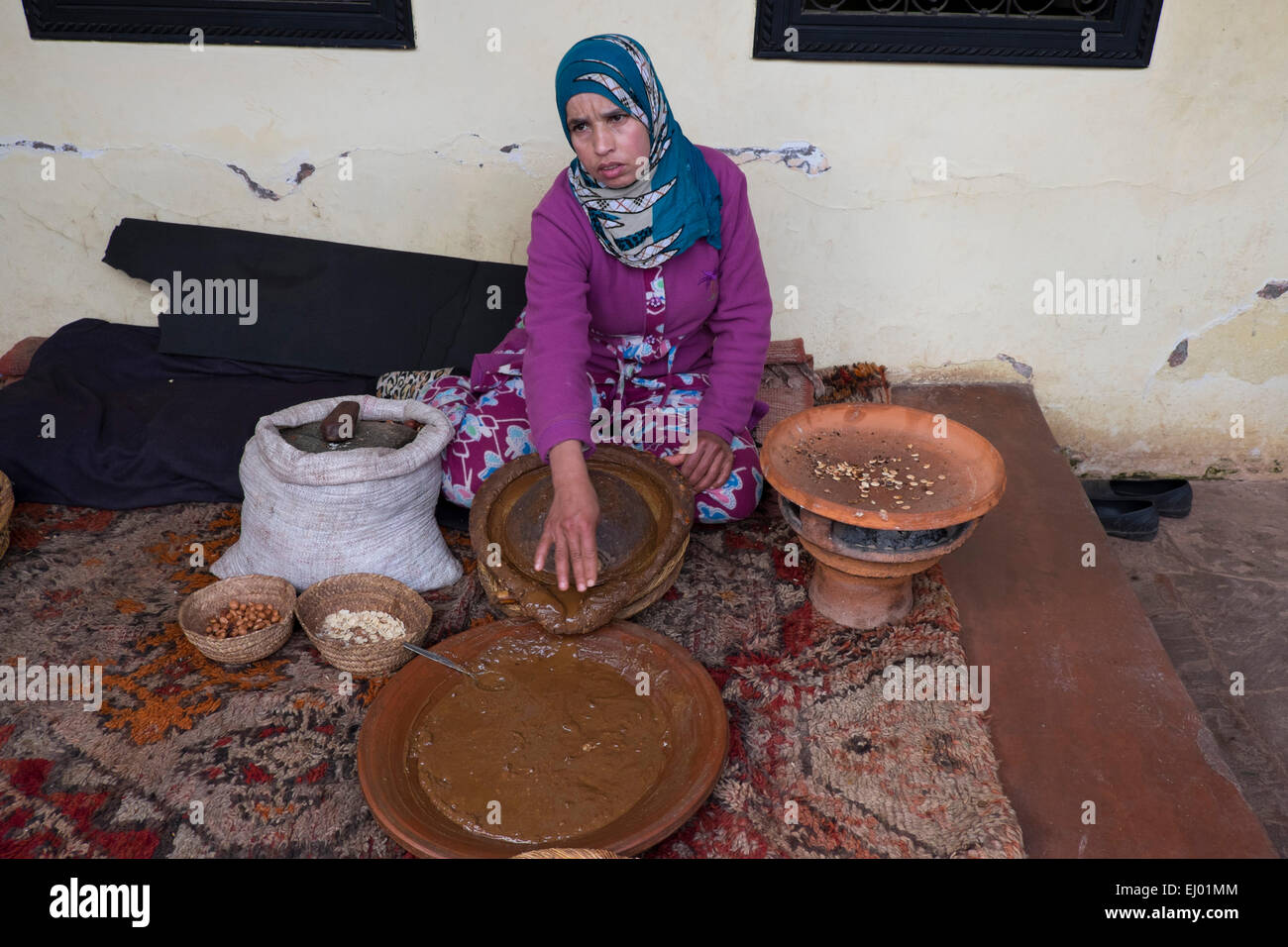 Woman grinding Argan (Argania spinosa) almonds  for the traditional manufacturing process of argan oil, Ourika Valley, Atlas Mou Stock Photo