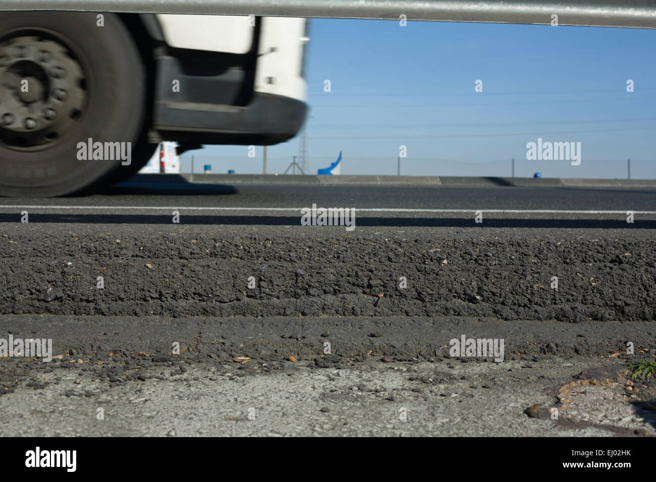 Truck wheels between dark asphalt road and rail guards. Motion shot Stock Photo