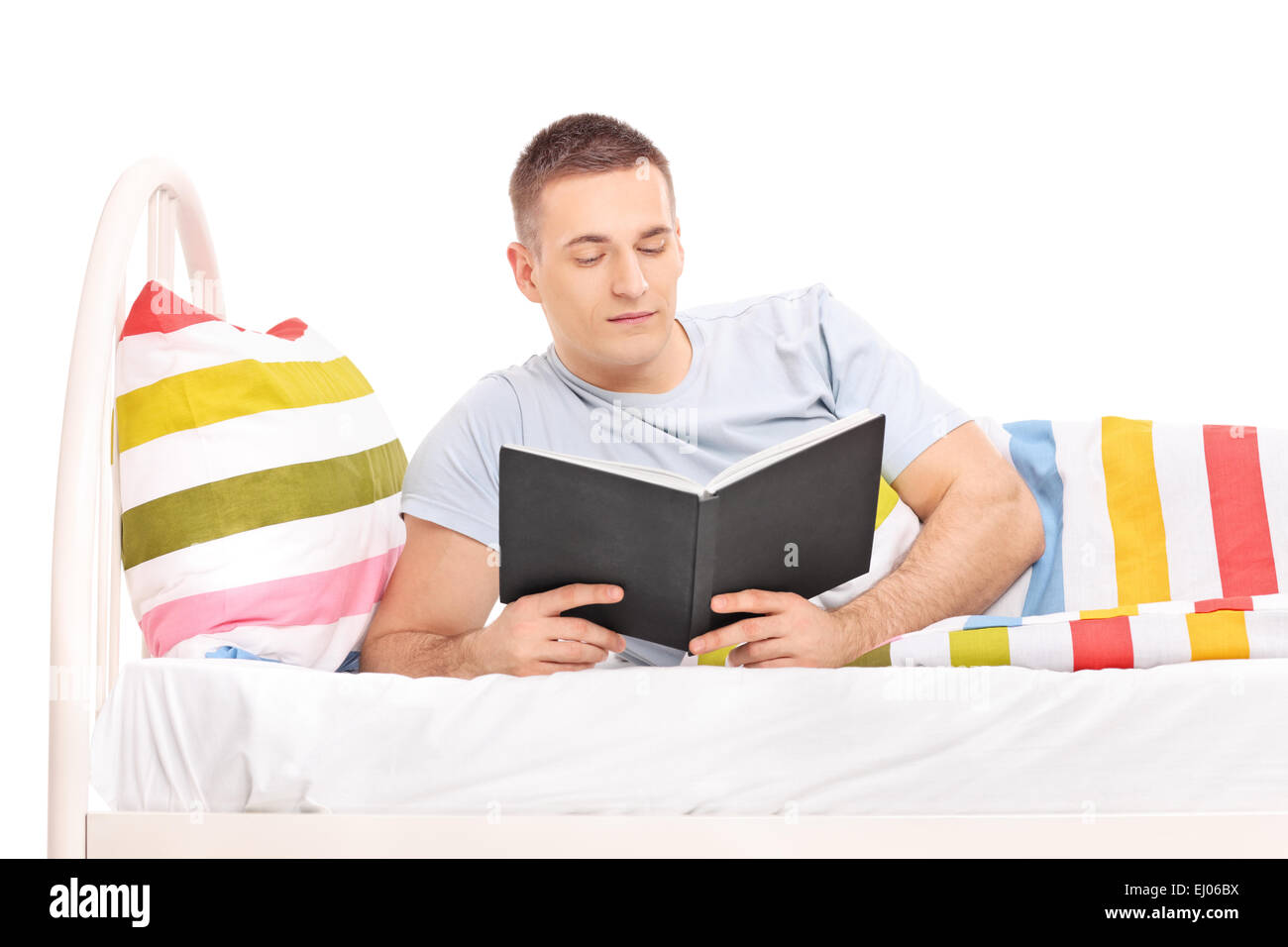 Handsome young man reading a book and lying in a comfortable bed