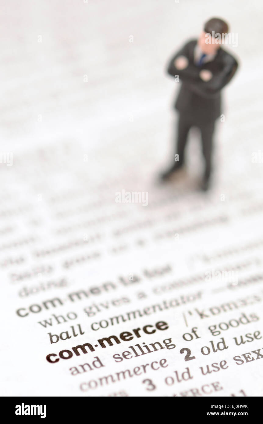 Businessman standing on the dictionary definition of 'commerce' Stock Photo