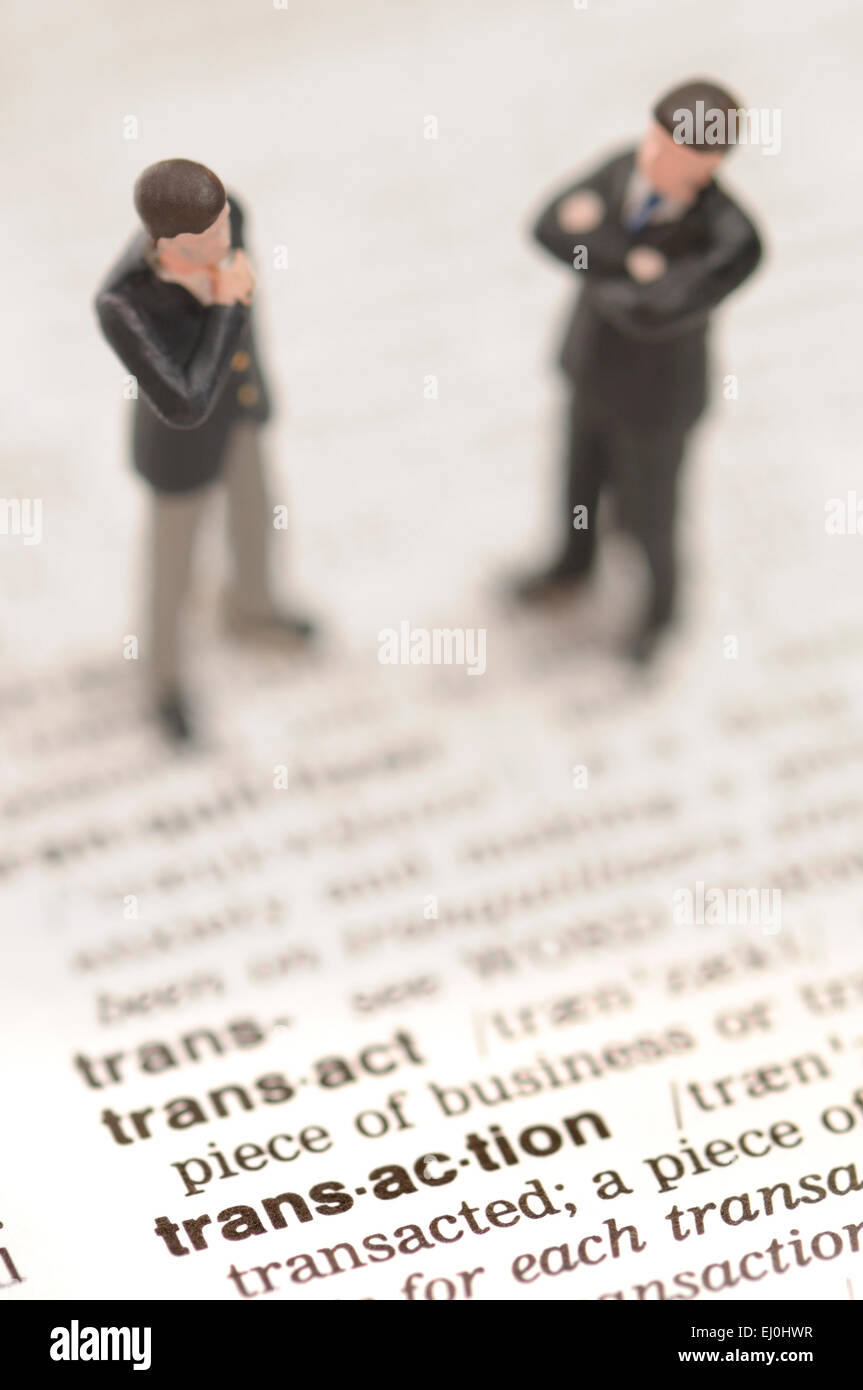 Businessmen standing on the dictionary definition of 'transaction' Stock Photo