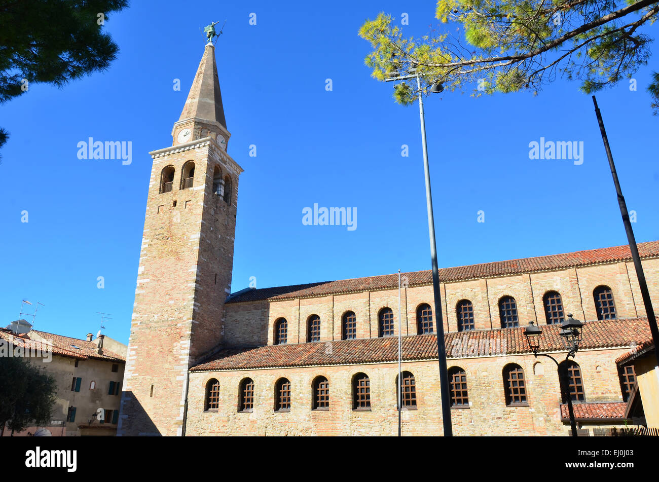 The ancient roman basilica of Saint Euphemia in Grado Italy. The clock tower is surmounted by the archangel Michael Stock Photo