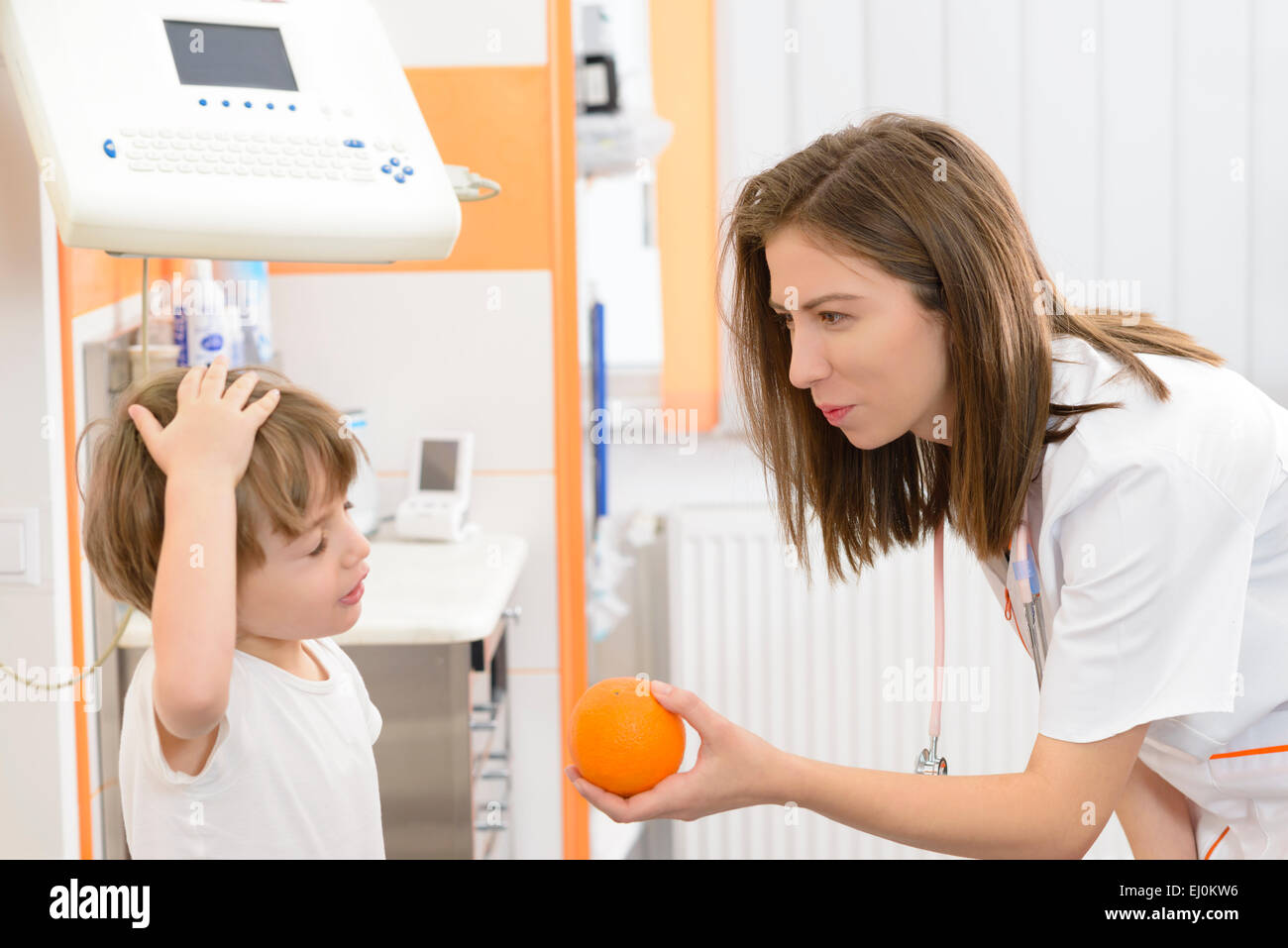 Angry kid refusing an orange at doctor visit Stock Photo