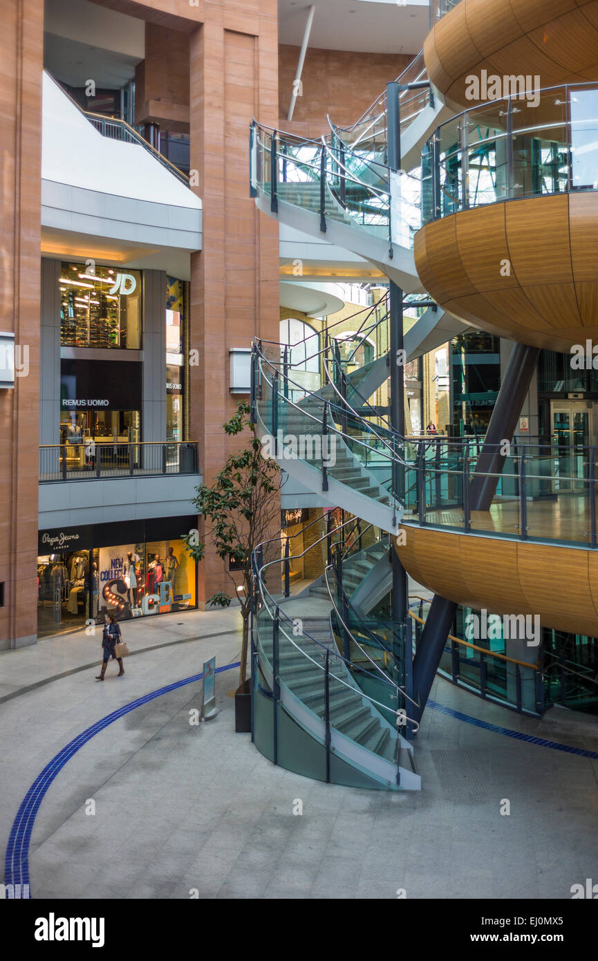 An isolated woman walking through an empty shopping centre.  Image taken from a height looking down.  Represents solitude and em Stock Photo