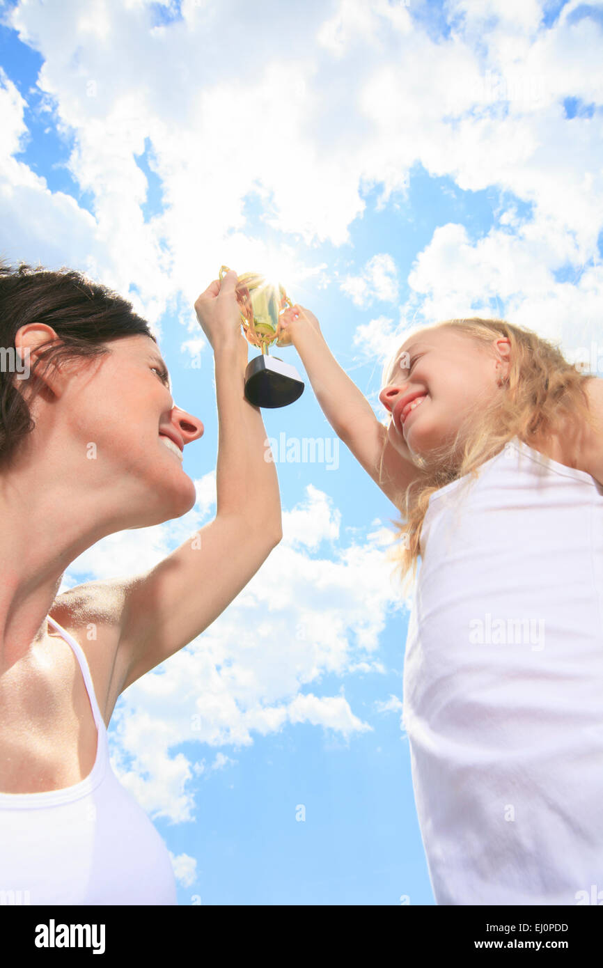 Happy mother and daughter holding a trophy high up Stock Photo