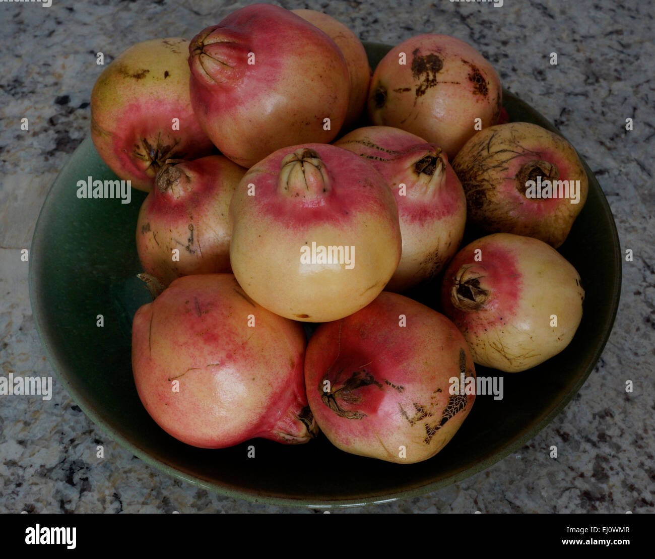 Freshly picked pomegranates in a green bowl. Stock Photo