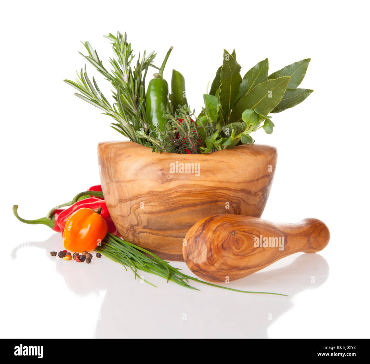 Various kind of fresh herbs in wooden grinder. Isolated on white