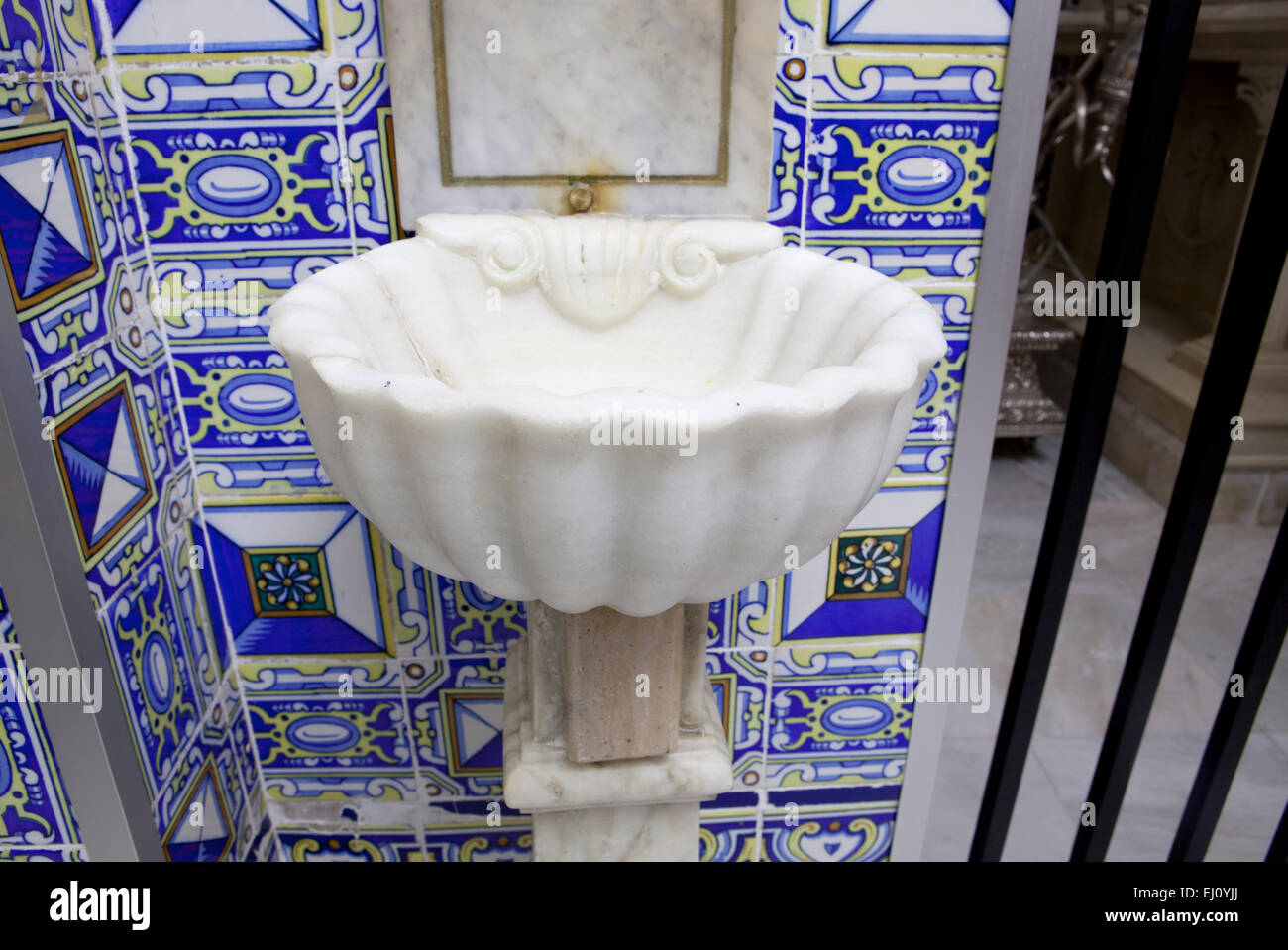 White marble baptismal font over typical spanish glazed tile decoration