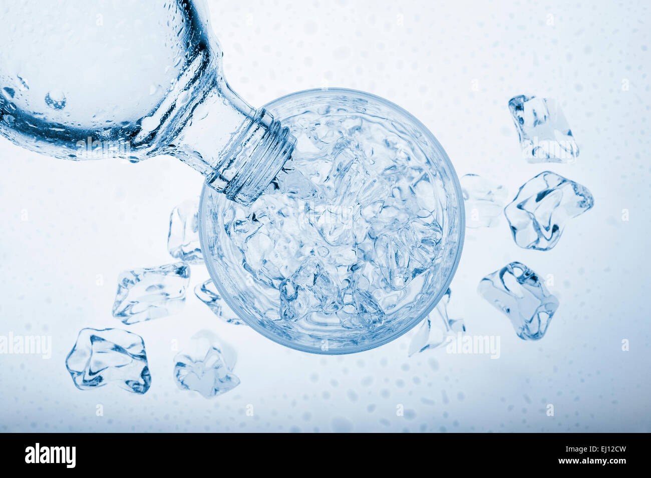 pouring water into glass with ice cube from a bottle, on blue background Stock Photo Alamy