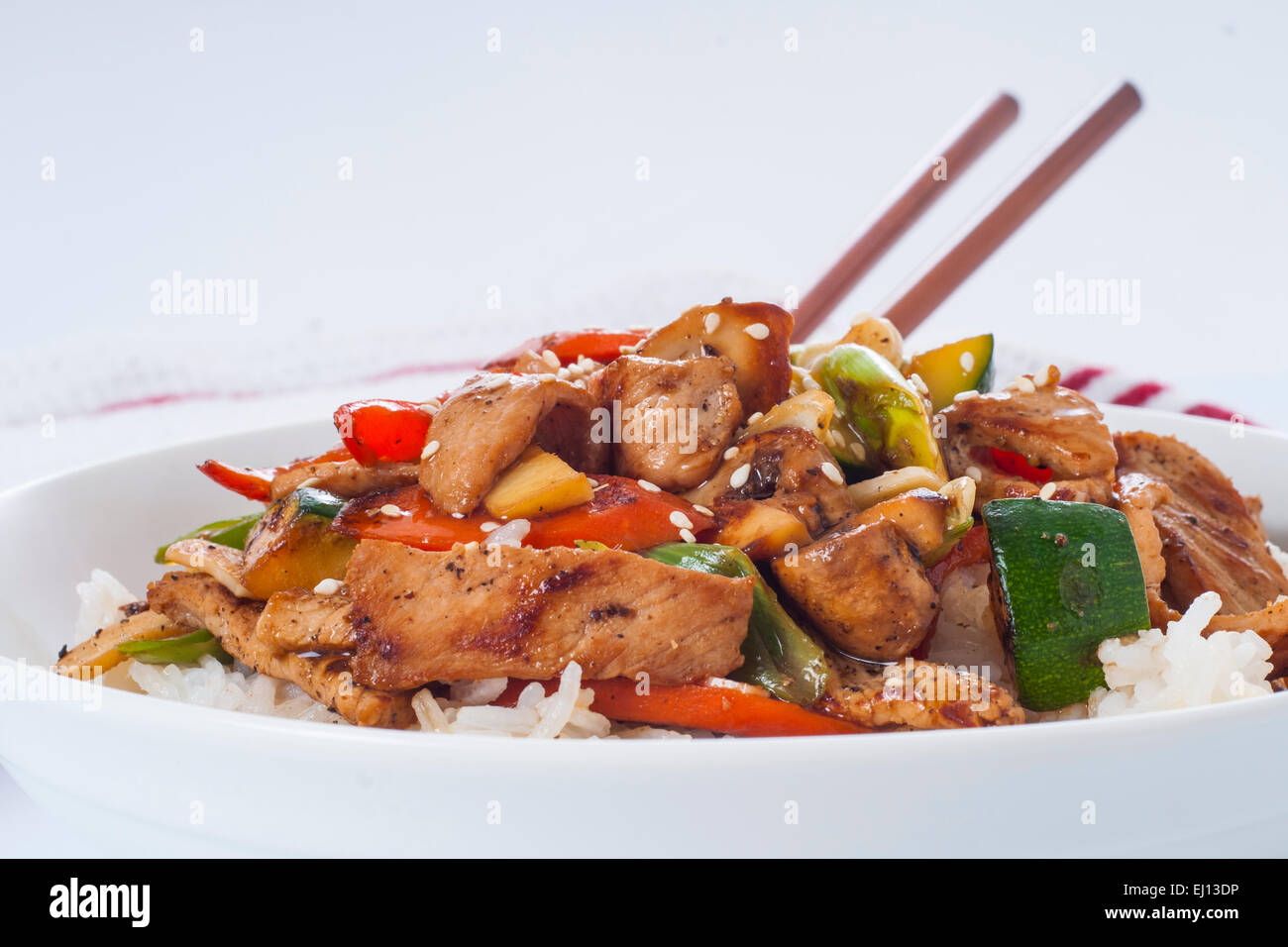 Bowl of homemade pork and stir fried vegetables on a bowl of white rice, with chopsticks Stock Photo