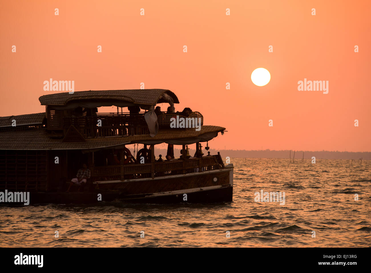 A houseboat in silhouette at sunset on the Vembanad Lake in Kumarakom, Kerala India Stock Photo