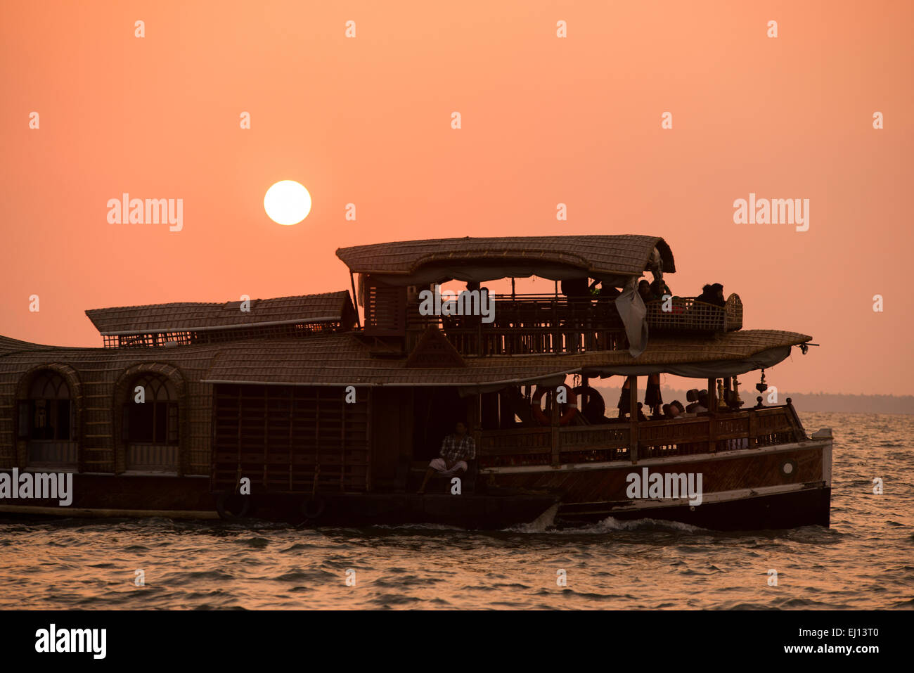 A houseboat in silhouette at sunset on the Vembanad Lake in Kumarakom, Kerala India Stock Photo