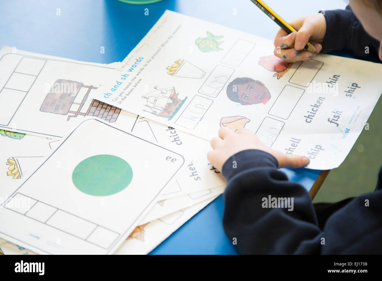 A UK primary school boy practising writing in a classroom Stock Photo