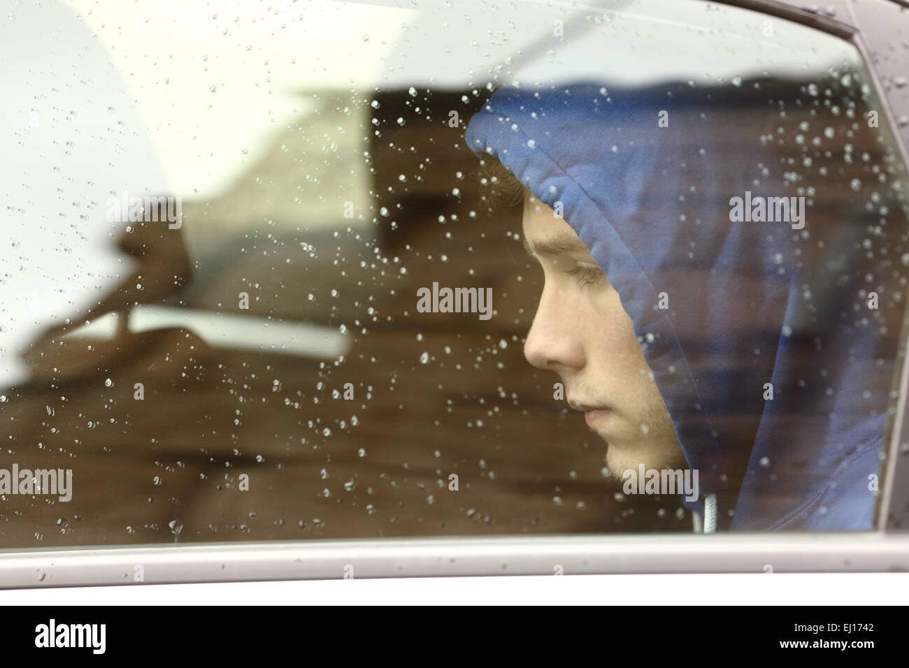 Sad teenager boy worried inside a car looking through the window Stock Photo