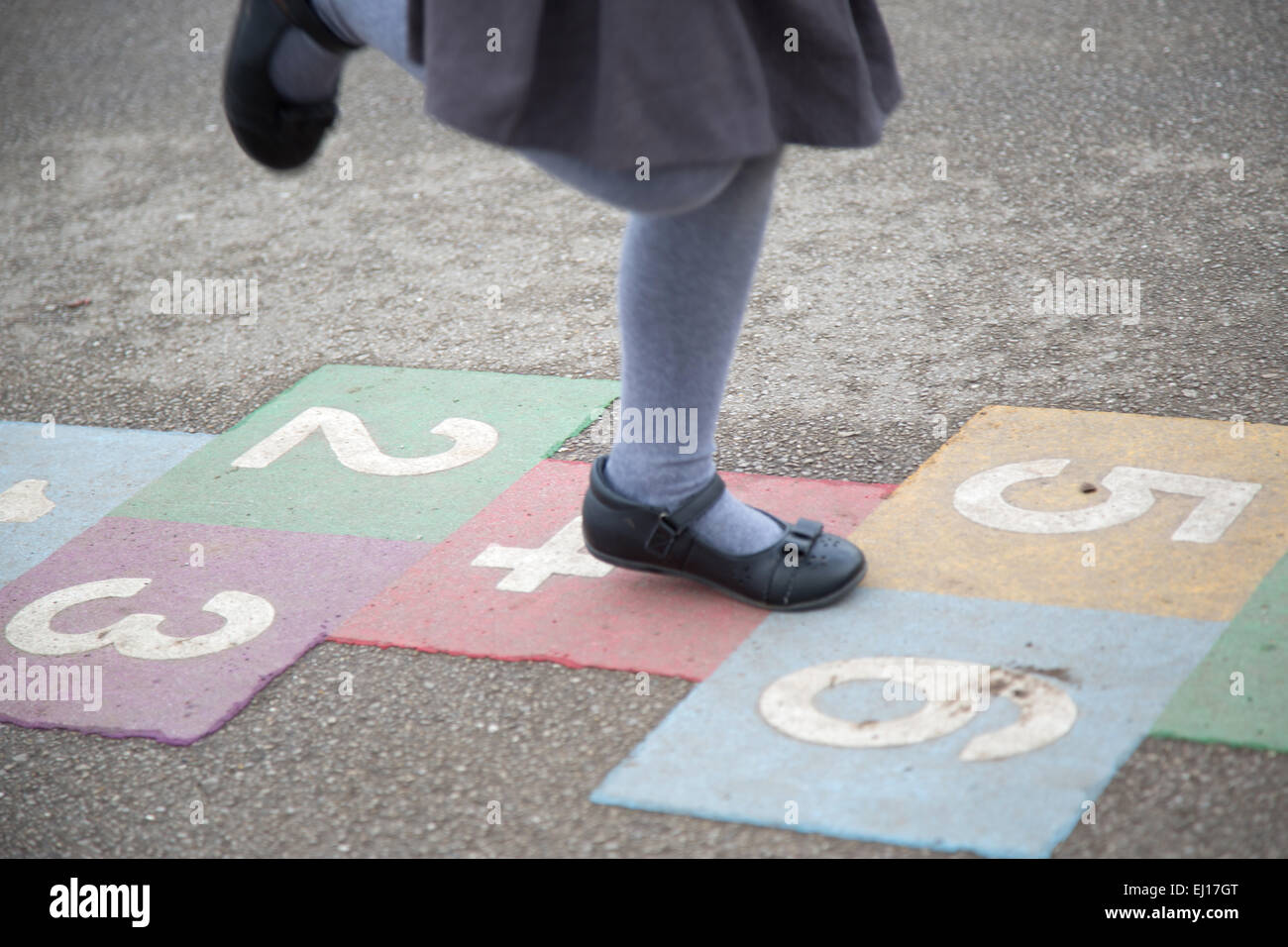 UK schoolgirl playing hopscotch in the playground of a UK primary school Stock Photo