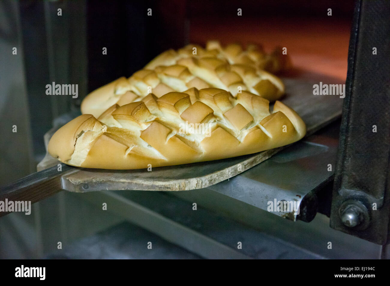 baking peel taking fresh baked bread from oven. Manufacturing process