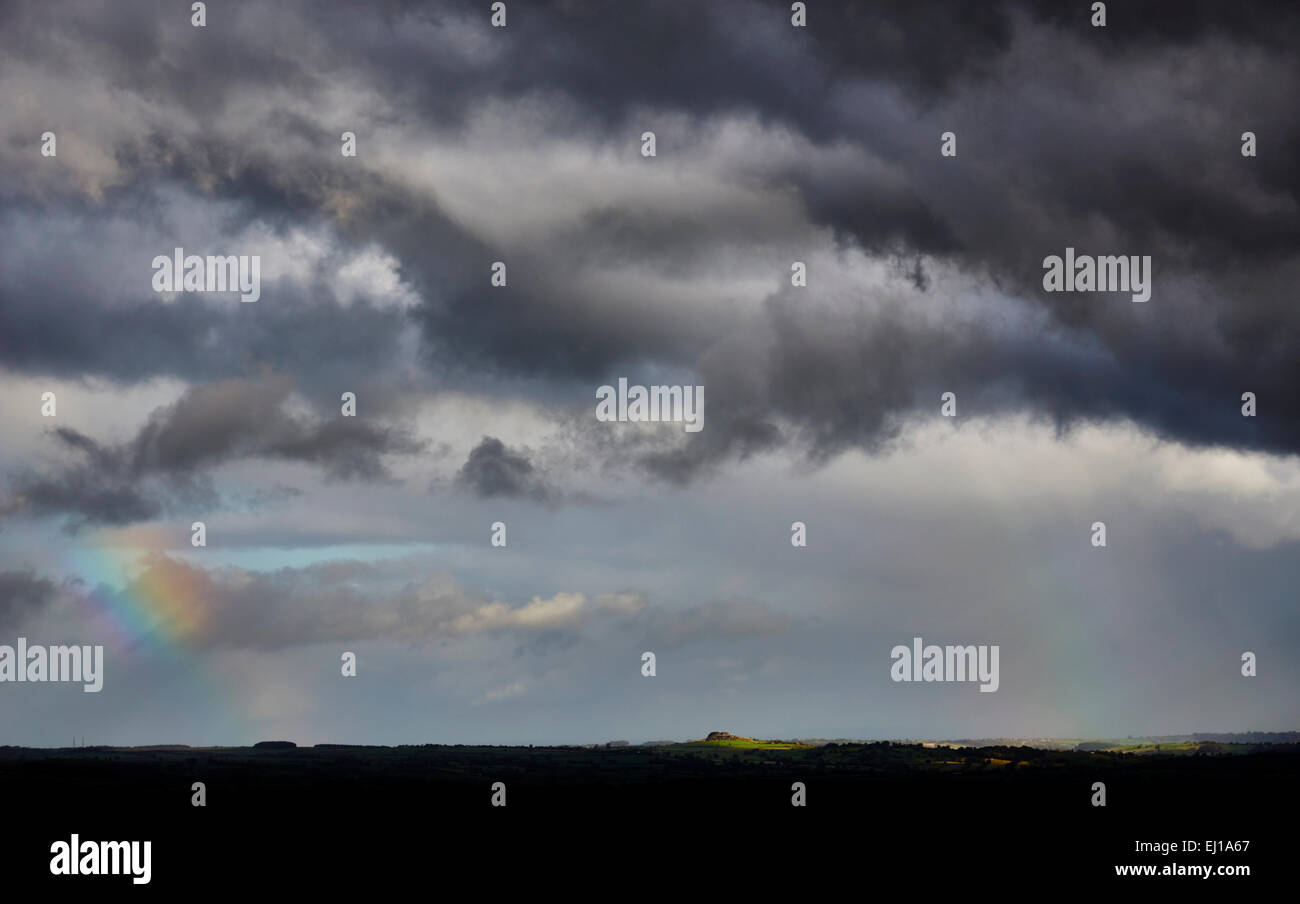 dark stormy skies over Almscliffe Crag Wharfedale valley with rainbow sky Stock Photo