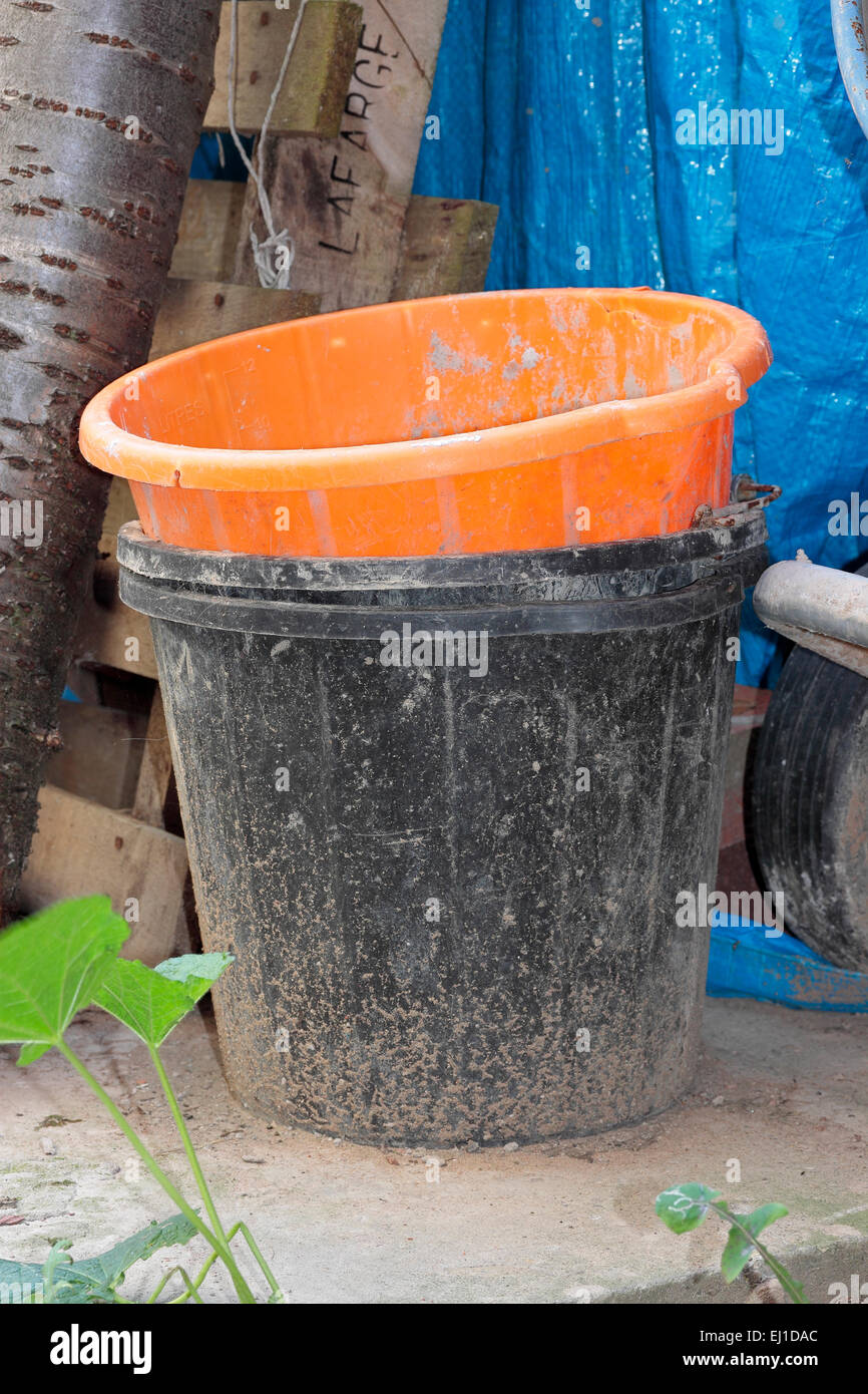 Dirty black and orange garden buckets Stock Photo