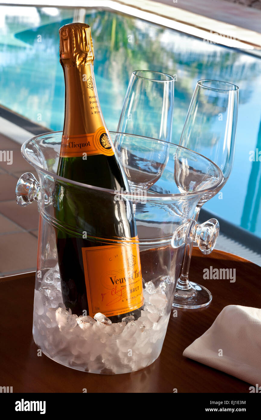 Veuve Clicquot fine vintage Champagne bottle with glasses, on ice in wine  cooler, luxury sunlit infinity pool behind Stock Photo - Alamy