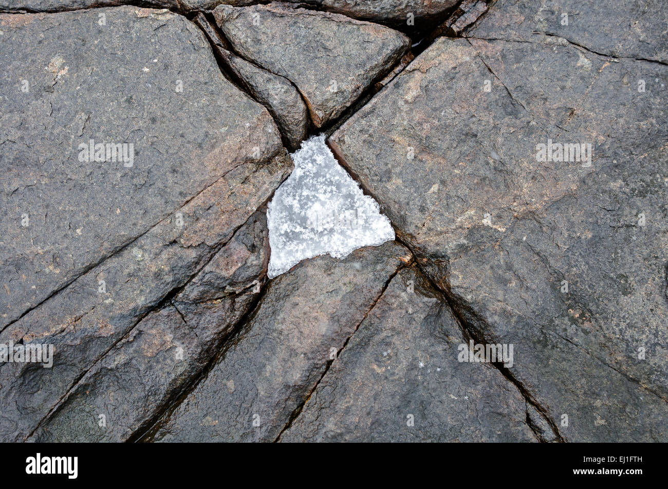 Ice fills a triangular crack in the granite shore of Acadia National Park, Bar Harbor, Maine. Stock Photo