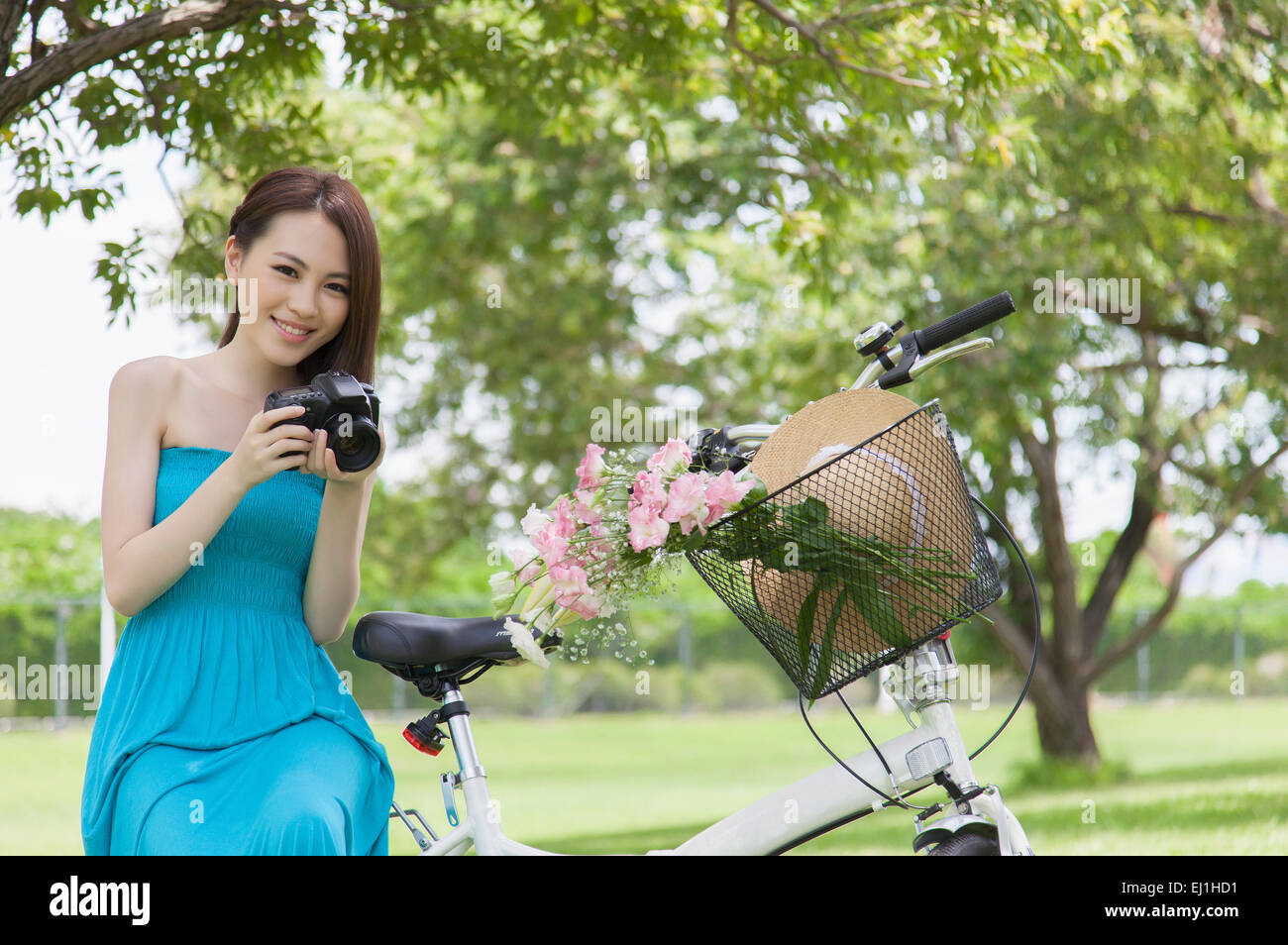 Young woman holding camera and smiling at the camera Stock Photo - Alamy