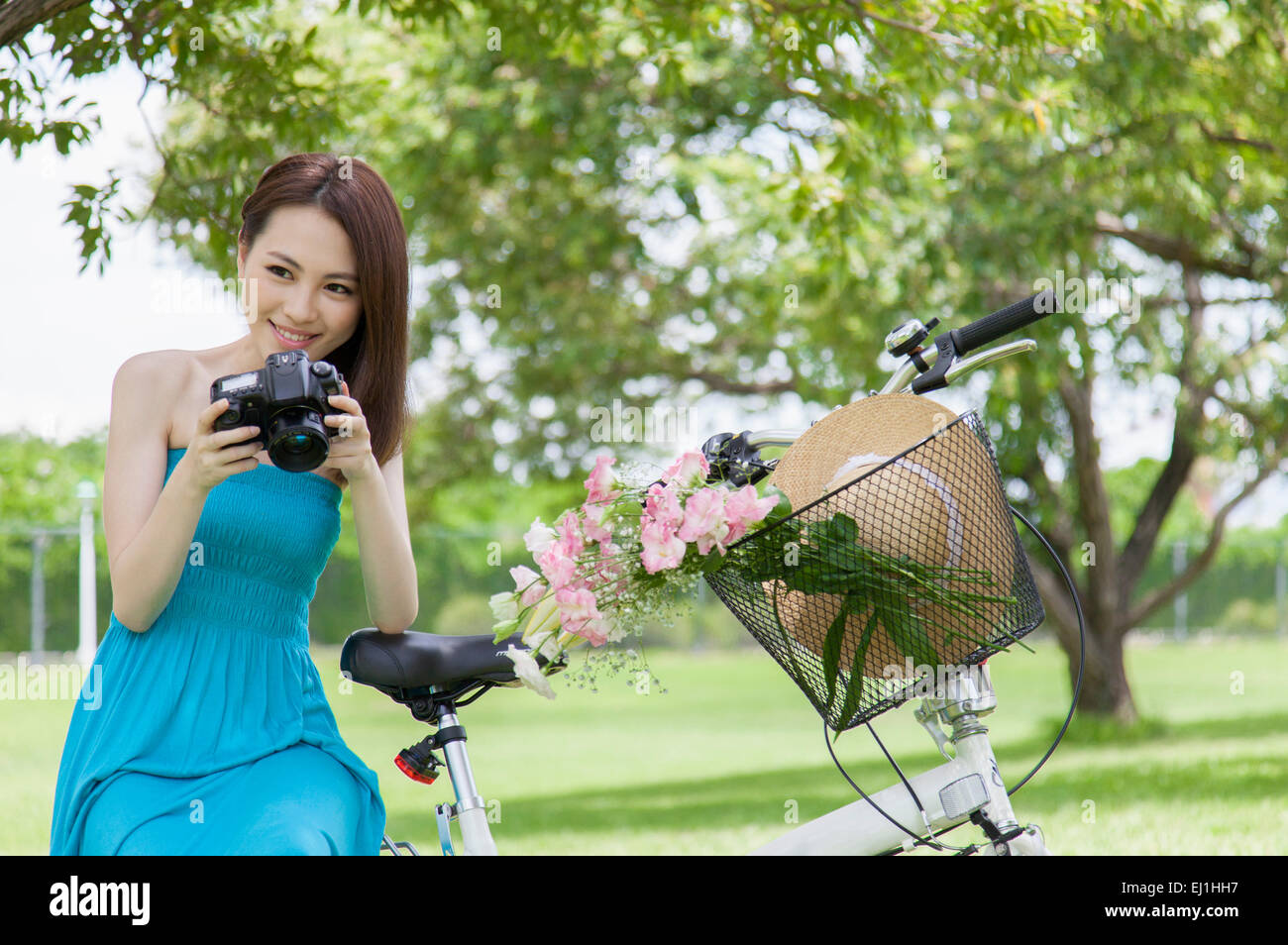 Young woman holding camera and smiling at the camera Stock Photo - Alamy