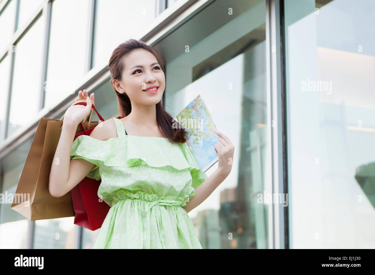 Young woman holding shopping bags and looking up with smile Stock Photo ...