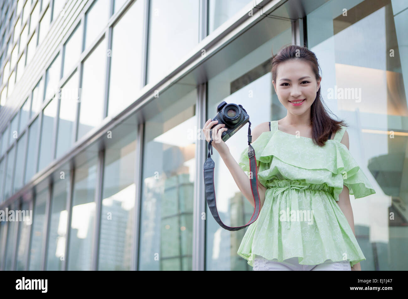 Young woman holding digital camera and smiling at the camera Stock ...