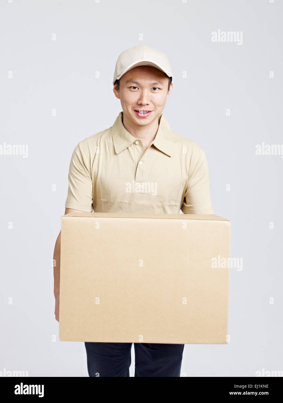 male asian delivery man carrying large cardboard box. Stock Photo