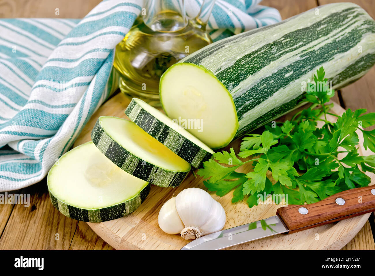 Zucchini green striped with garlic and oil on board Stock Photo