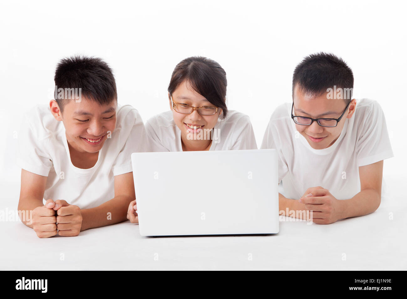 Teenagers lying on front and looking at the laptop together Stock Photo